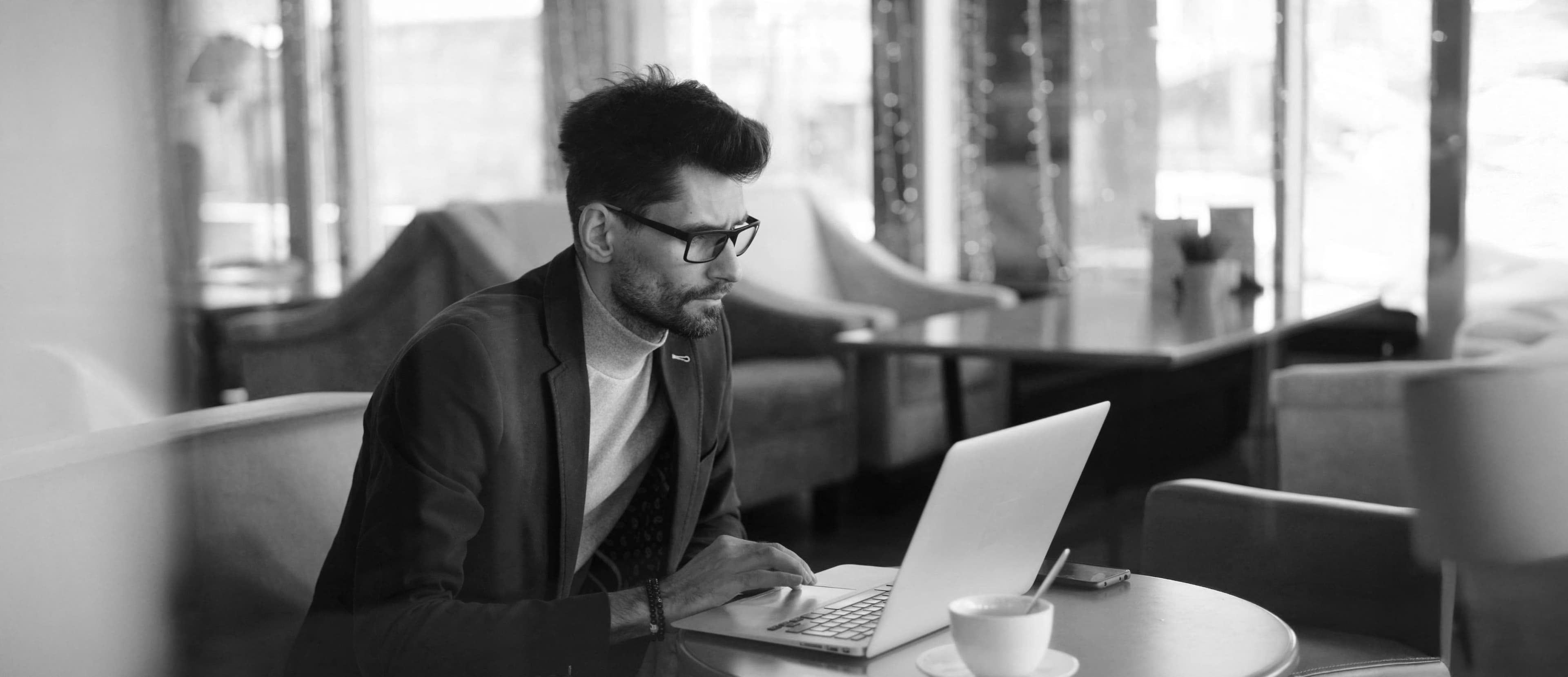 Black and white photograph of man working on laptop